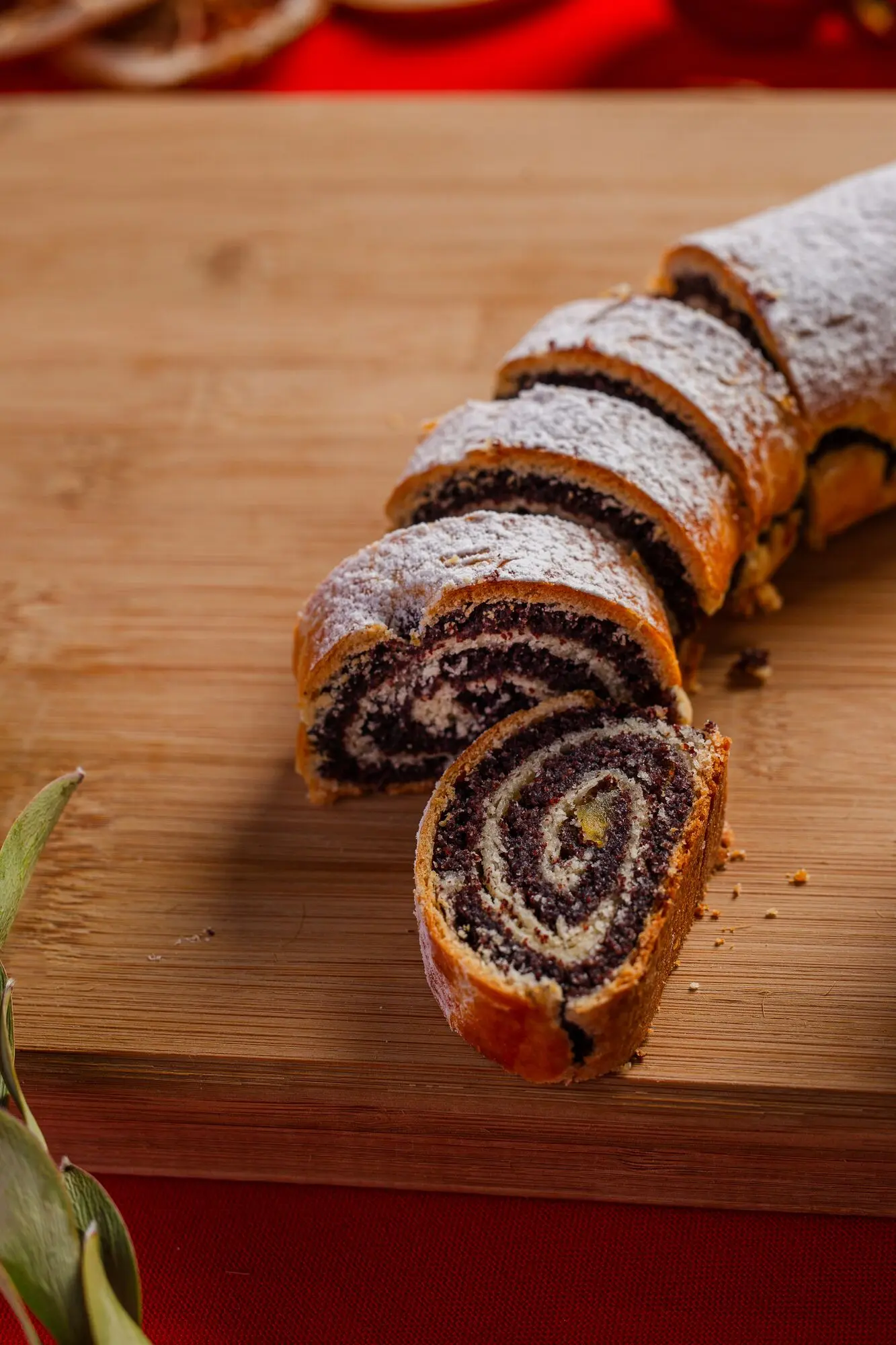 Szeletelt mákos bejgli porcukorral, fa vágódeszkán